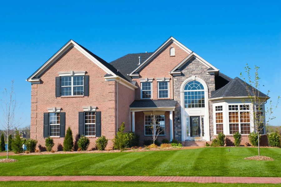 beautiful brick new home construction with green and well-maintained lawn